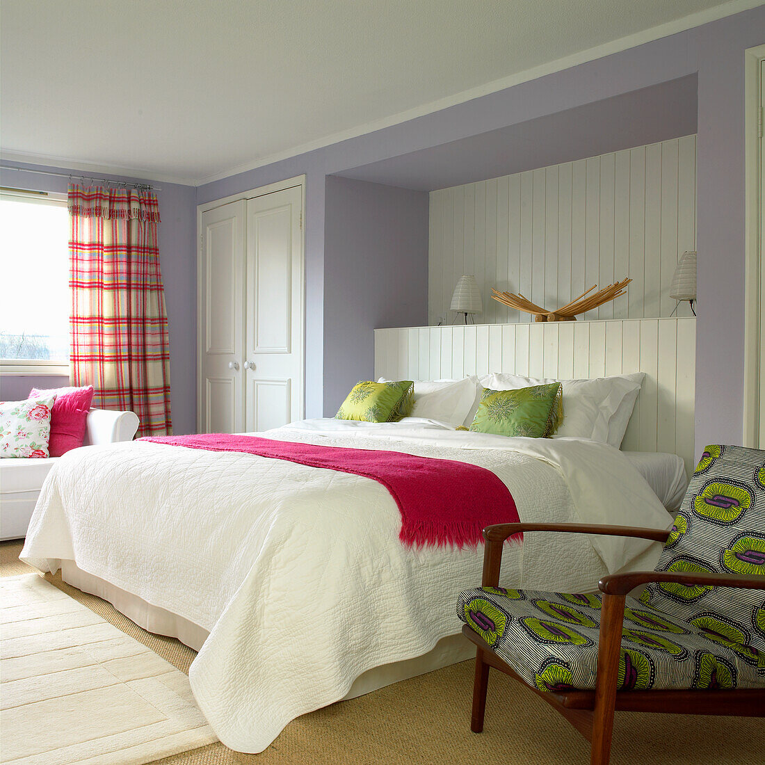 Helles Schlafzimmer mit Holzbett, weißer Bettwäsche und farbigen Akzenten
