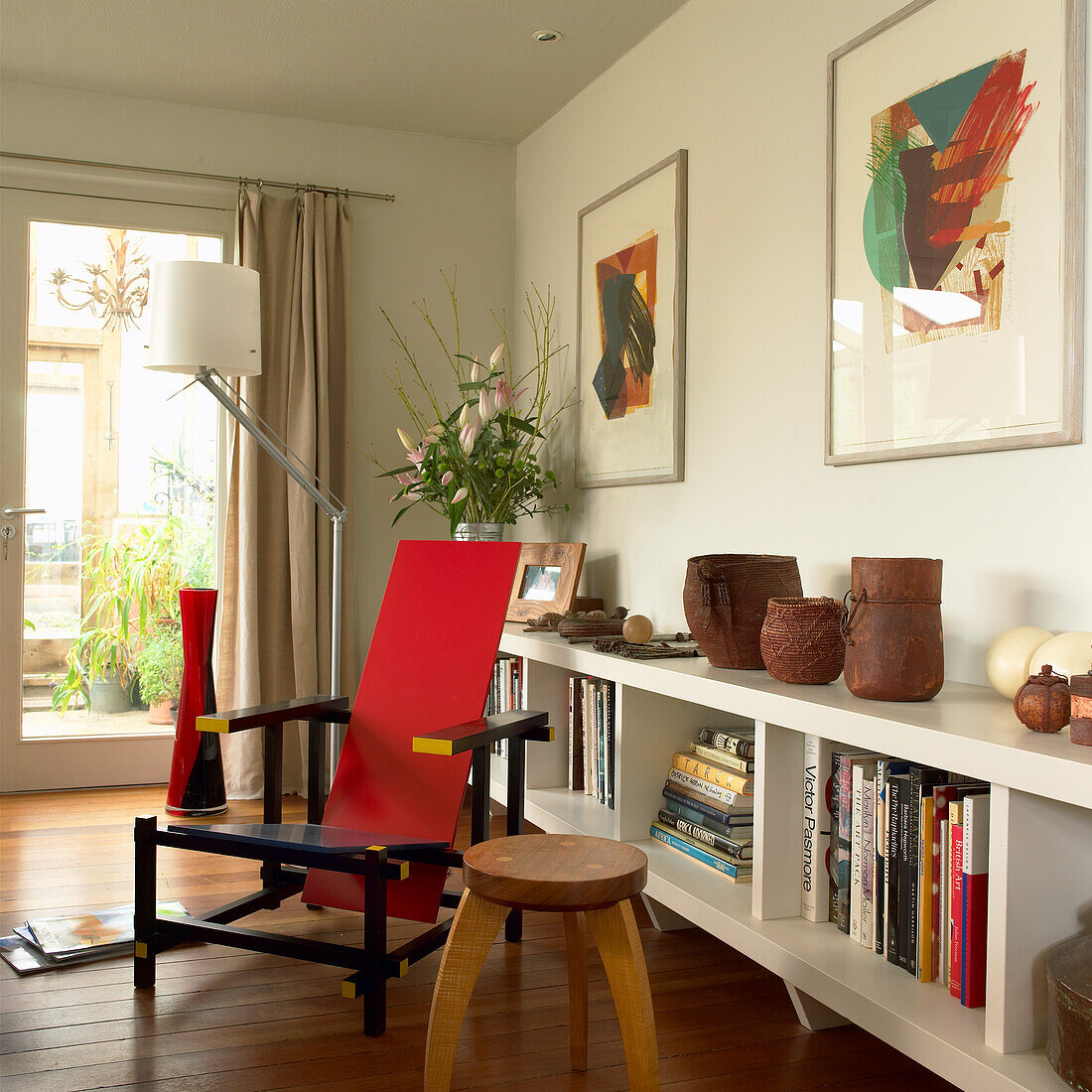 Leseecke mit rotem Designersessel und Bücherregal im modernen Wohnzimmer