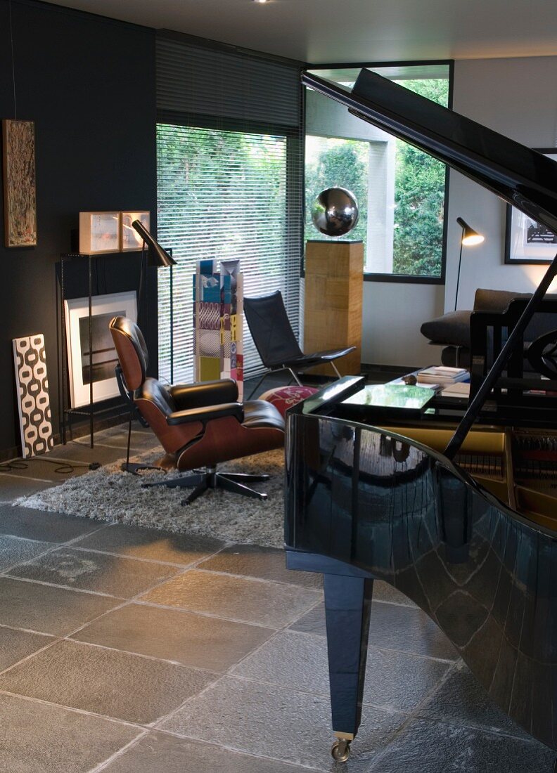 Schwarzer Klavierflügel in modernem Wohnraum mit grauen Fliesenboden