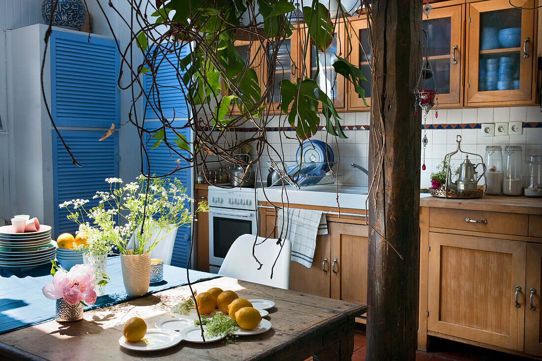 Rustic kitchen with wooden furniture and blue accents, lemons and flowers on wooden table