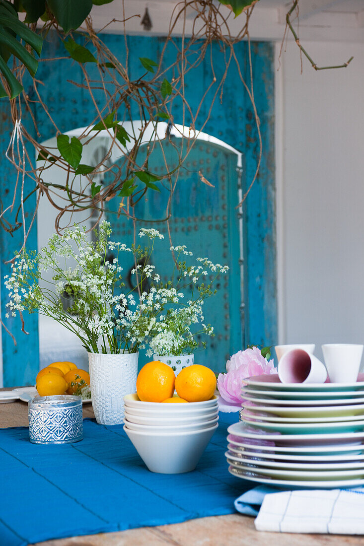 Geschirr und Blumenarrangement auf Holztisch mit blauem Tischläufer