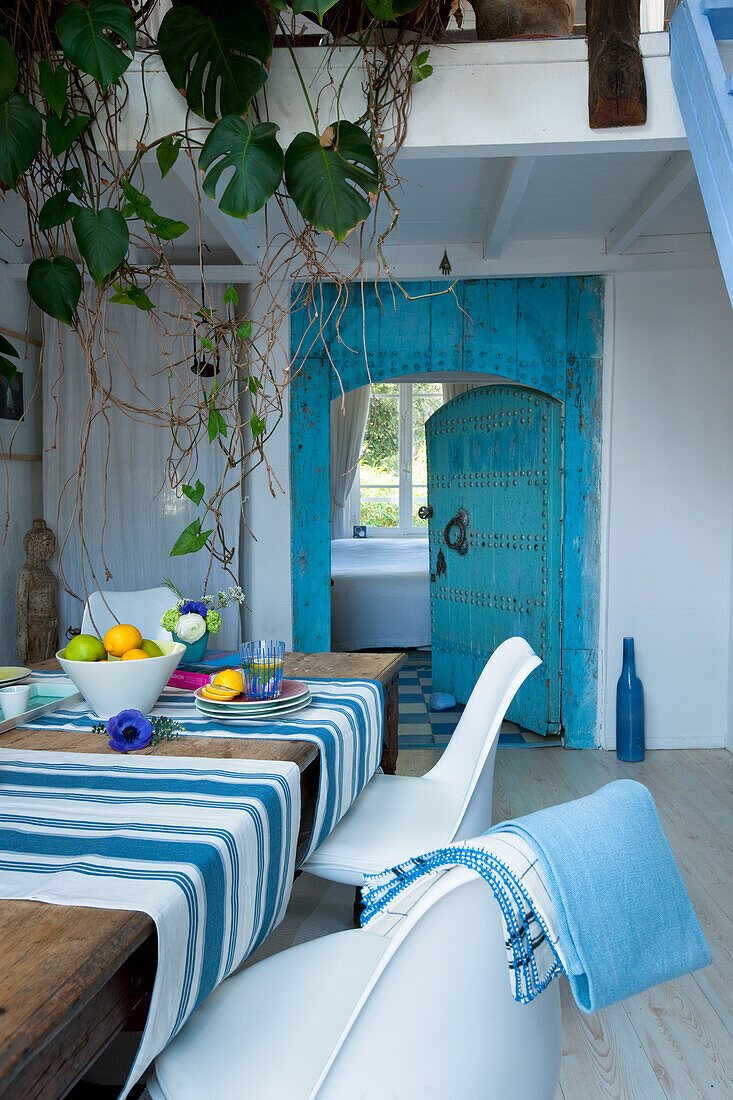 Dining area with wooden table, striped table runners and turquoise-coloured antique door