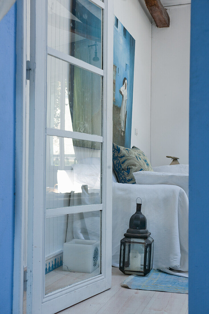 View into room with painting, white walls, blue accents and lantern