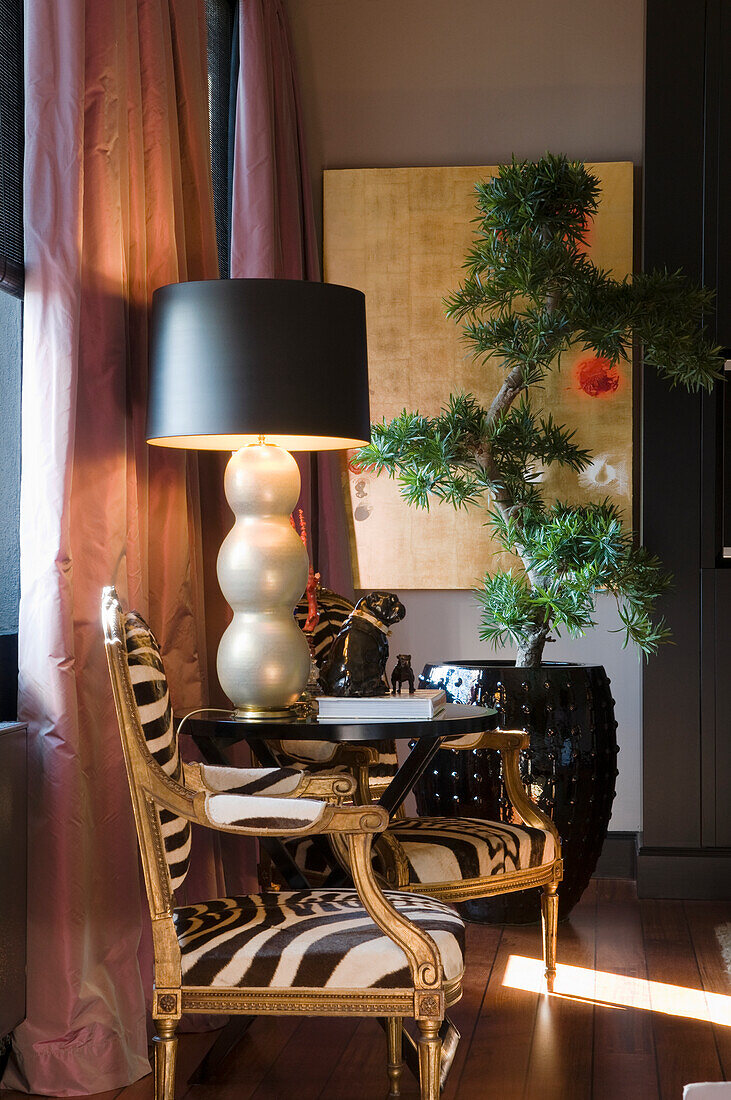 Sessel mit Zebramuster und goldenen Details, Stehlampe und Bonsai