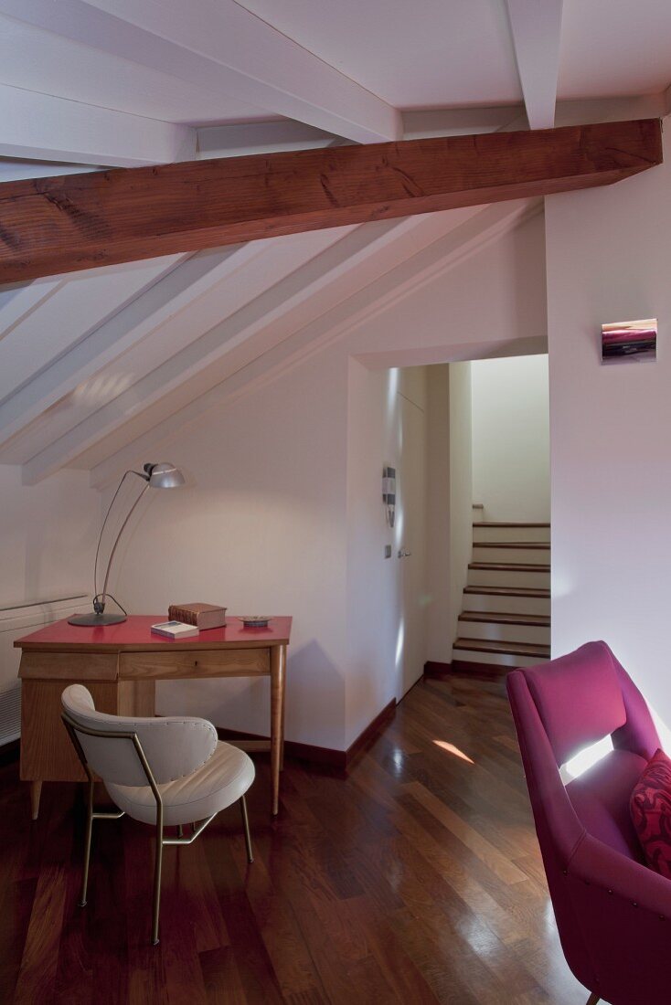 Moderner Wohnraum unterm Dach mit kleiner Schreibtischecke im Retrostil; durch farbig unterschiedlich behandelte Holzbalken betonte Dachschräge