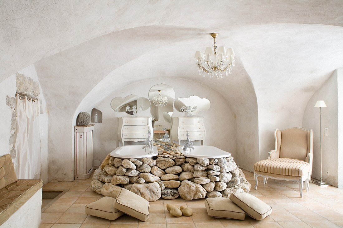 Twin bathtubs embedded in boulders in Baroque-style bathroom