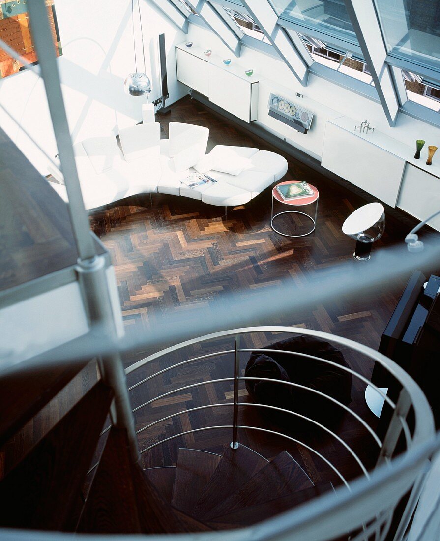 Blick auf Wendeltreppe und Designersofa im offenen Wohnraum
