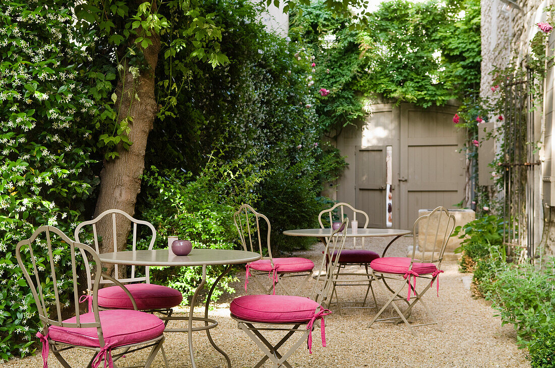 Seating area with metal furniture and pink cushions in the courtyard