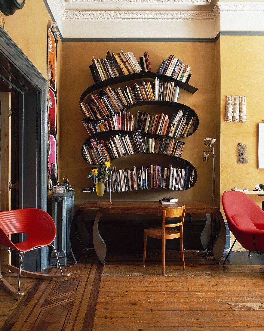 Stilmix im traditionellen Wohnraum mit geschwungenem Bücherregal im Designerstil über postmodernem Wandtisch