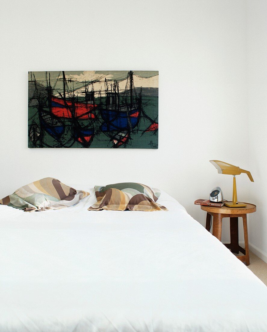Doppelbett mit Kissen und modernem Bild mit Schiffmotiven an Wand