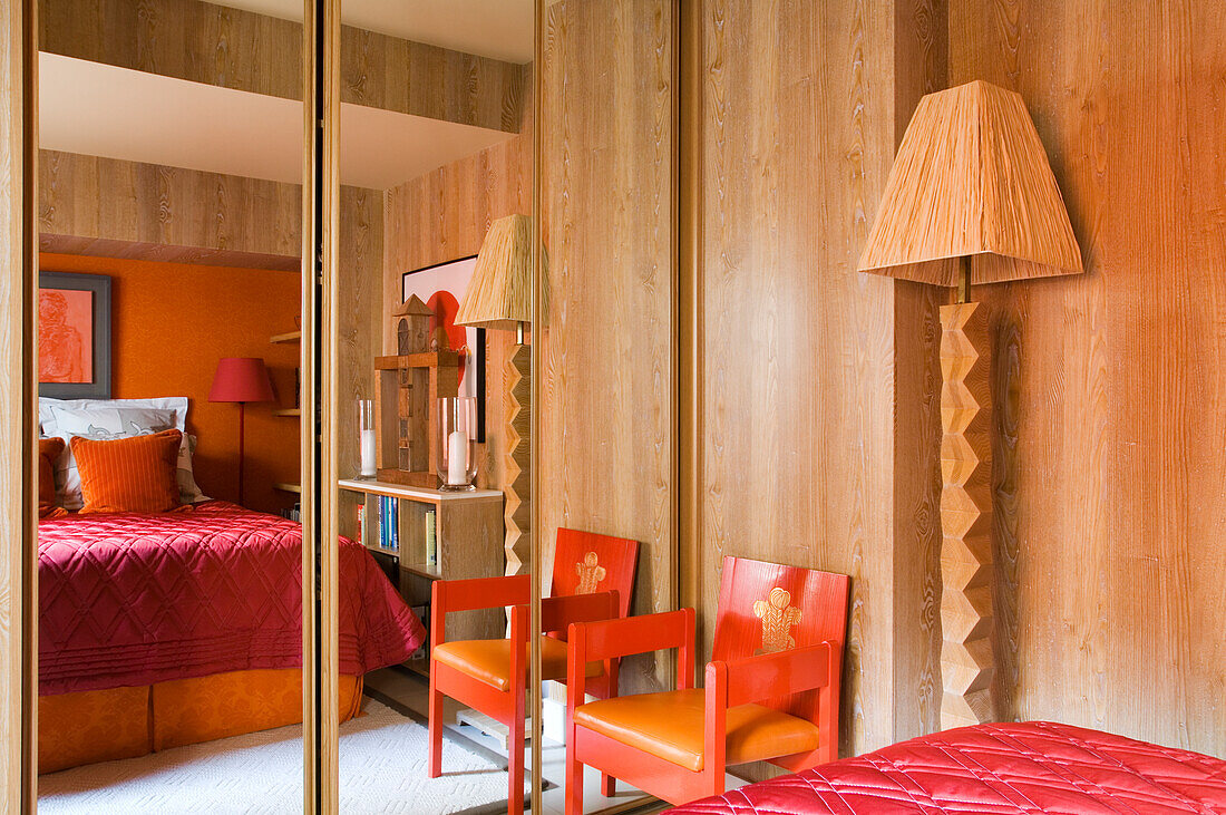 Bedroom with furnishings in wood and red, mirrored wardrobe