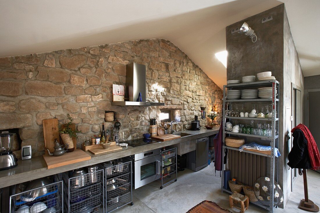 Moderne Küchenzeile vor Natursteinwand im Dachgeschoss