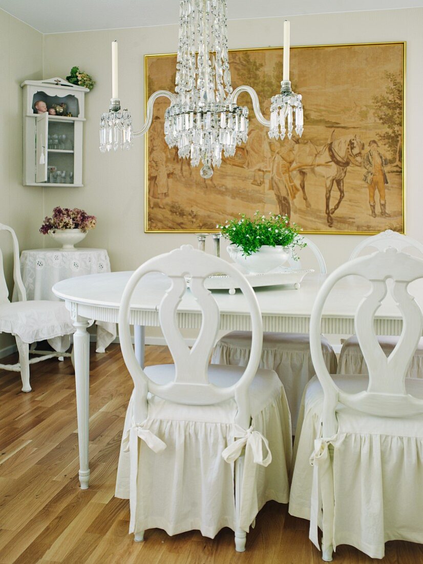 Romantisches Vintage-Esszimmer in Weiß mit Kronleuchter und Kohlezeichnung an der Wand