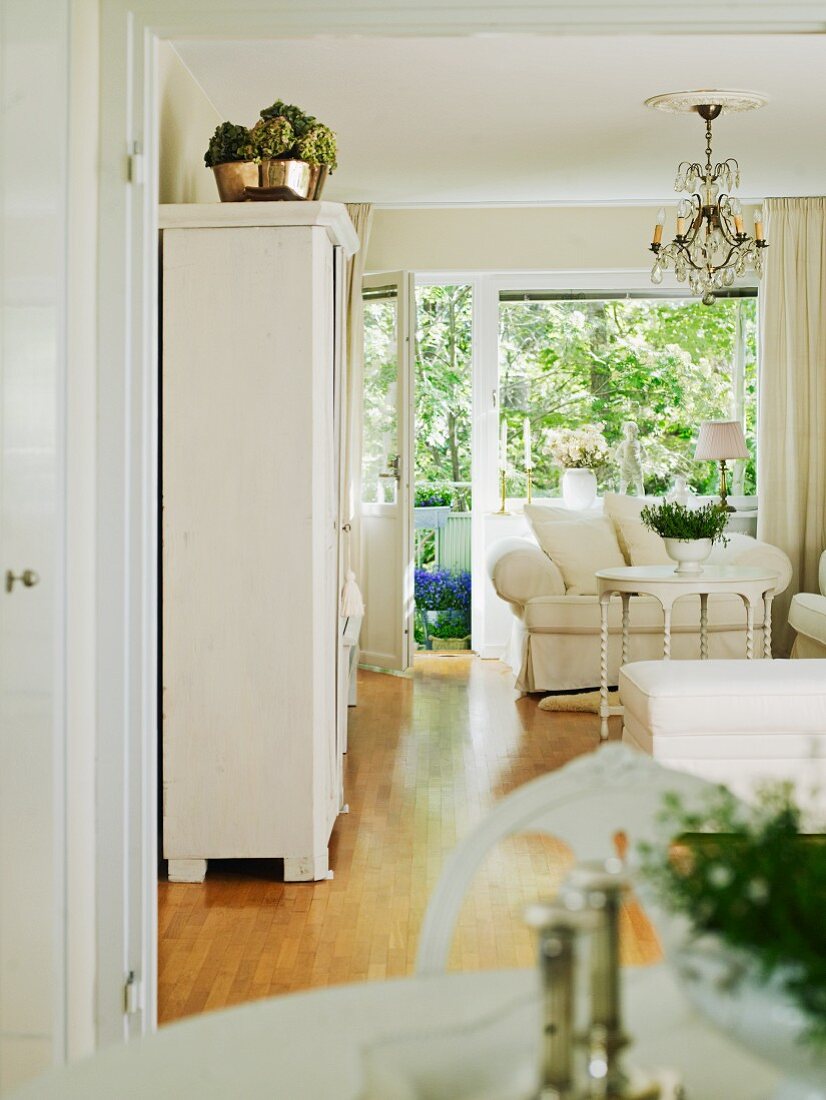 Klassische, weiße Vintageeinrichtung im Wohnzimmer mit Blick auf Fensterfront und Balkontür
