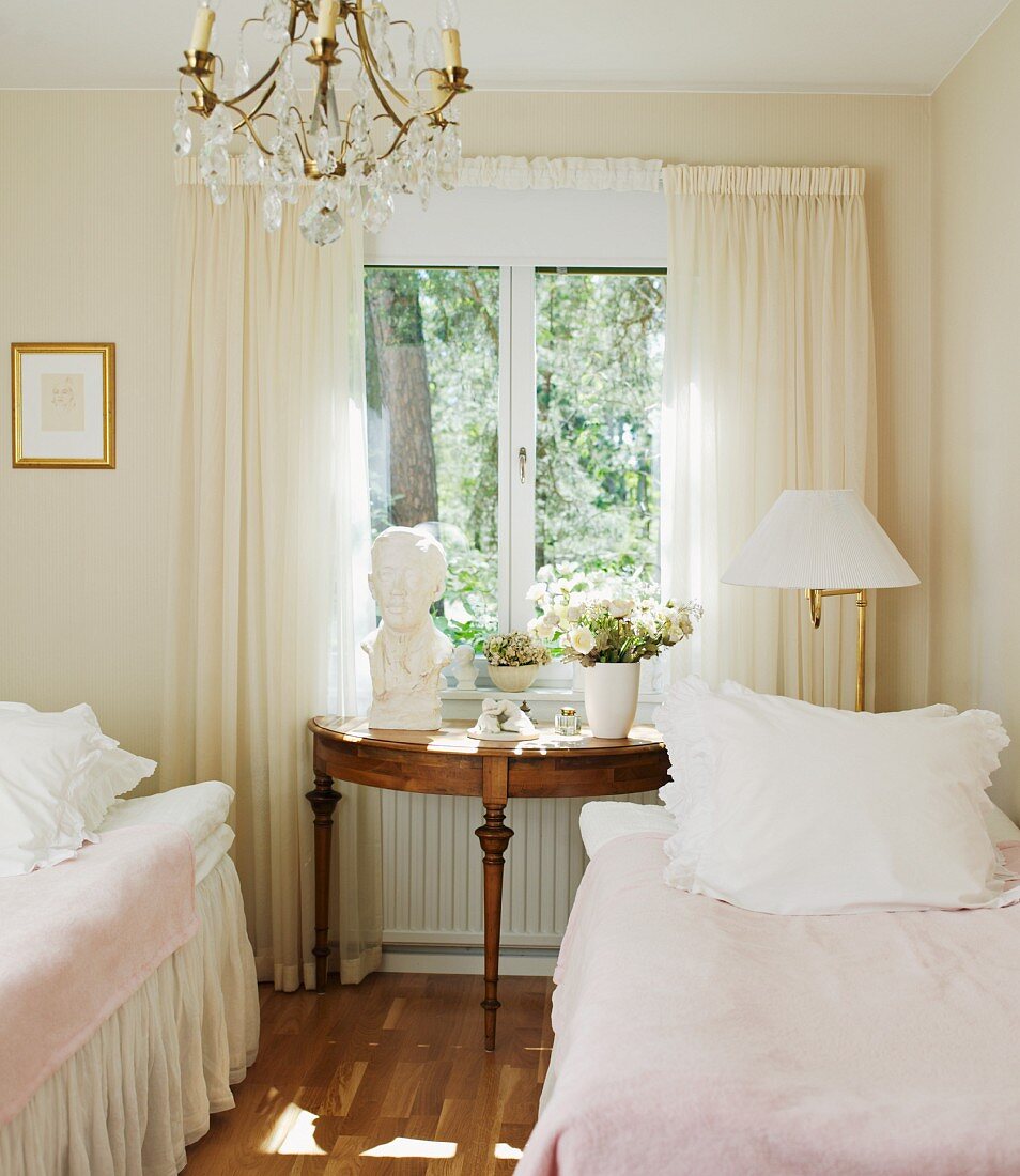 Romantischer Vintagestil im Gästezimmer mit klassischem Wandtisch vor dem Fenster und Volantsbetten