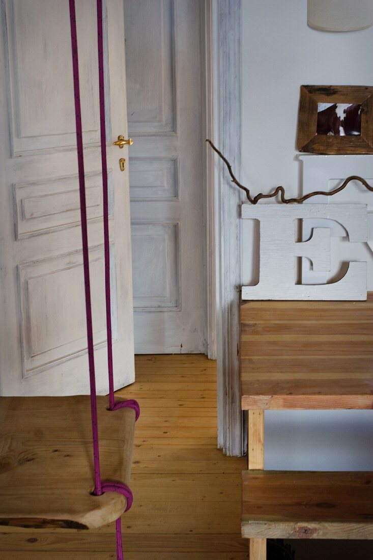 Von Decke abgehängte Schaukel und offen stehende Tür in rustikalem Ambiente