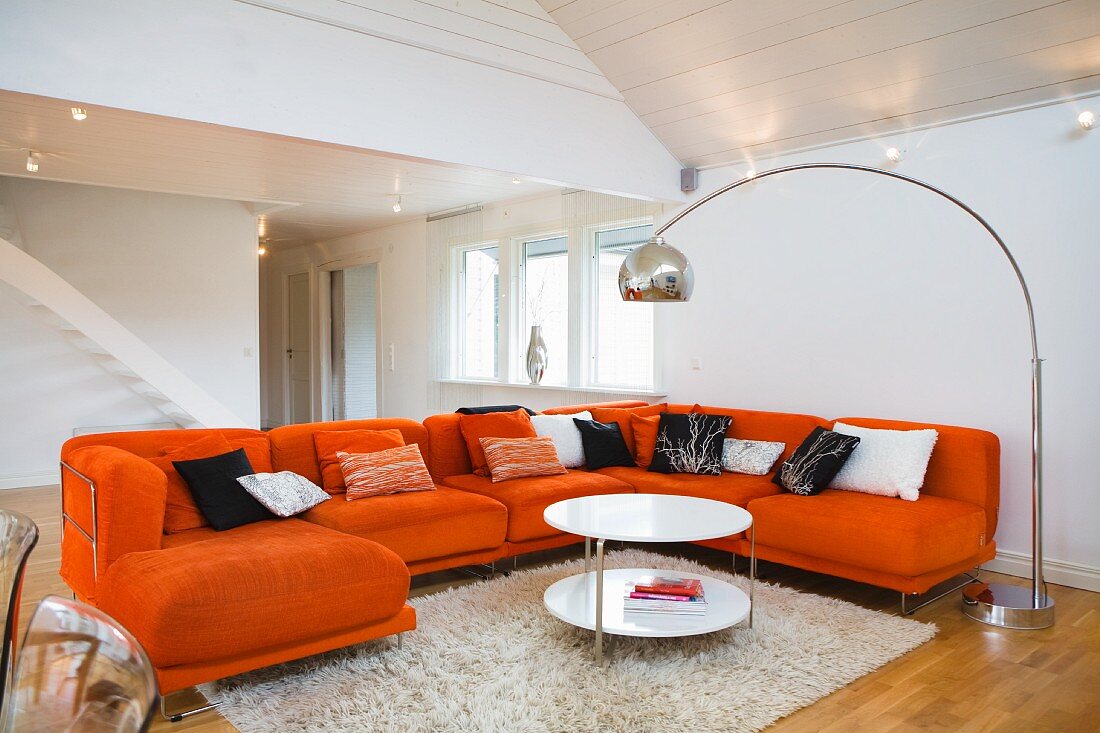 Orangefarbene Couchgarnitur und Bogenlampe im Wohnzimmer eines Schwedenhauses