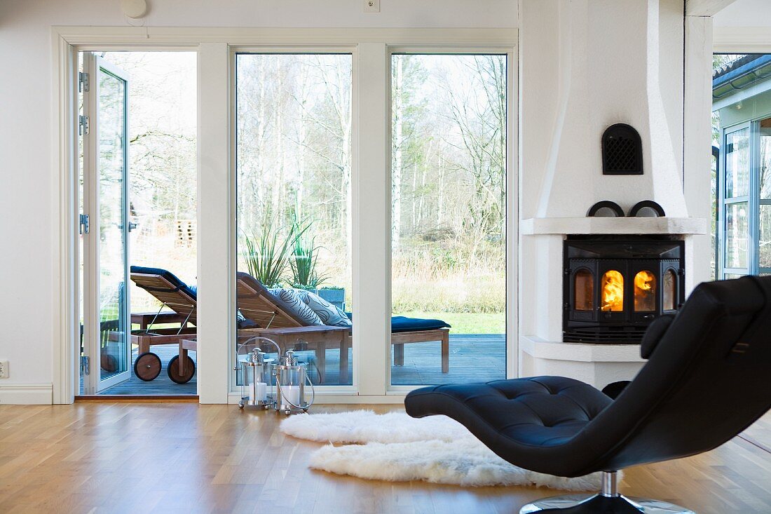 Black designer couch in front of fireplace with view of terrace