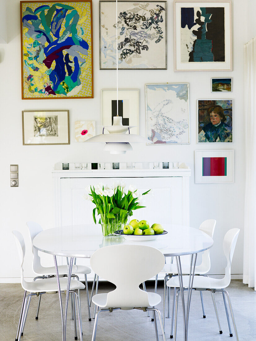 Weißer Esstisch mit Stühlen und Kunstwerken an der Wand