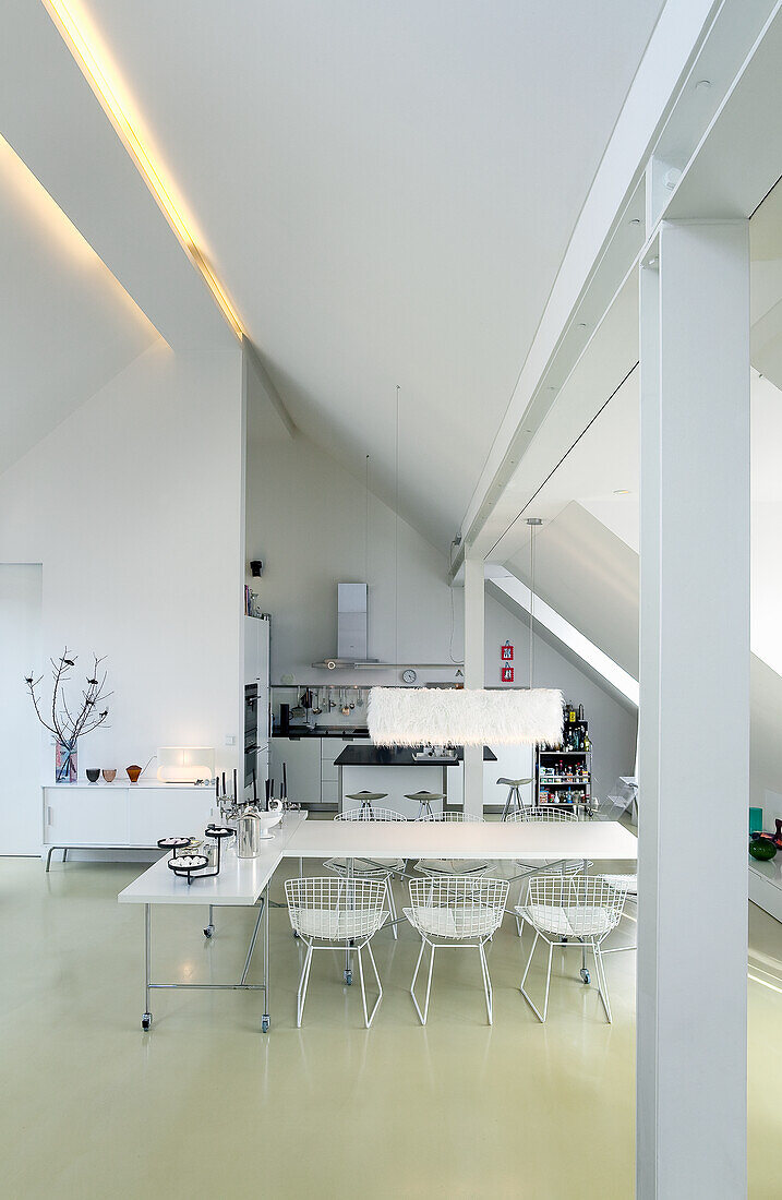 Open-plan living room with kitchen and dining table under a sloping roof