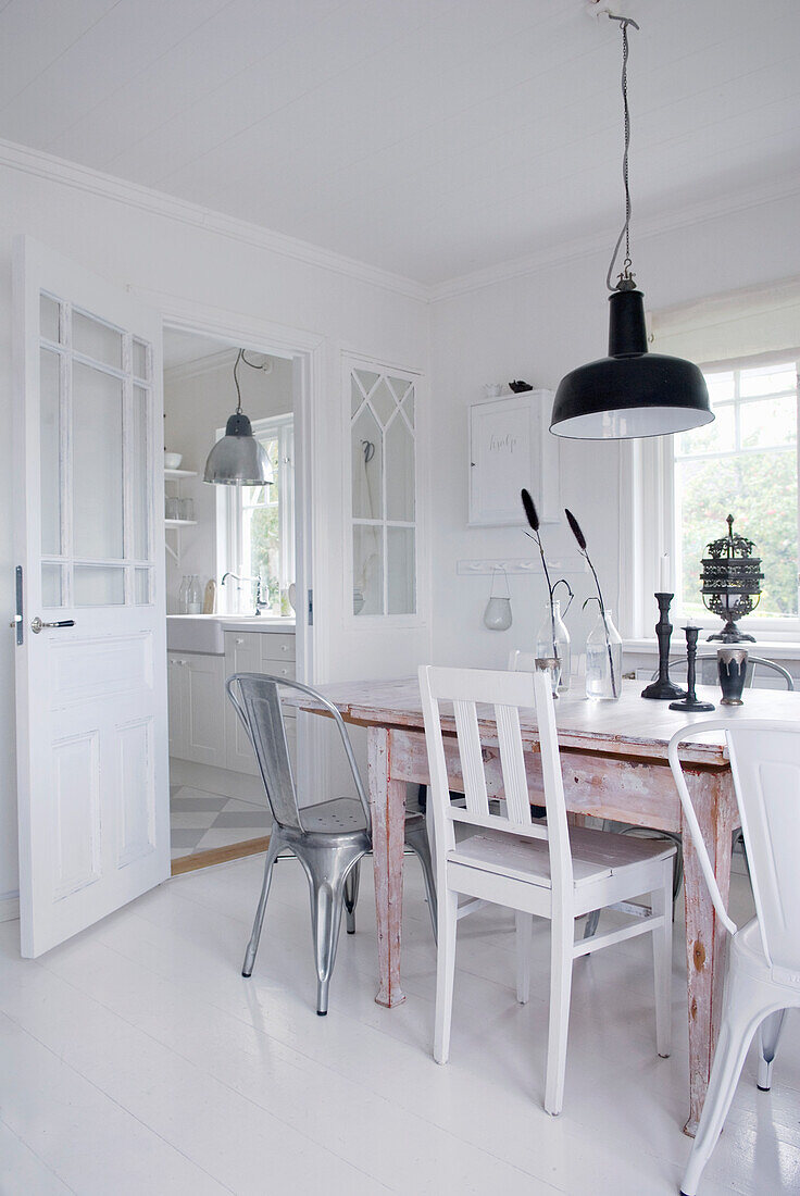 White dining room with industrial pendant light and vintage chairs