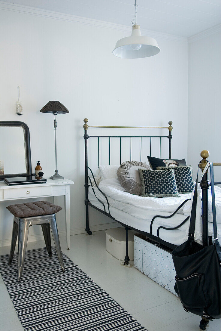 Metal bed with decorative pillows, dressing table and stool in bedroom