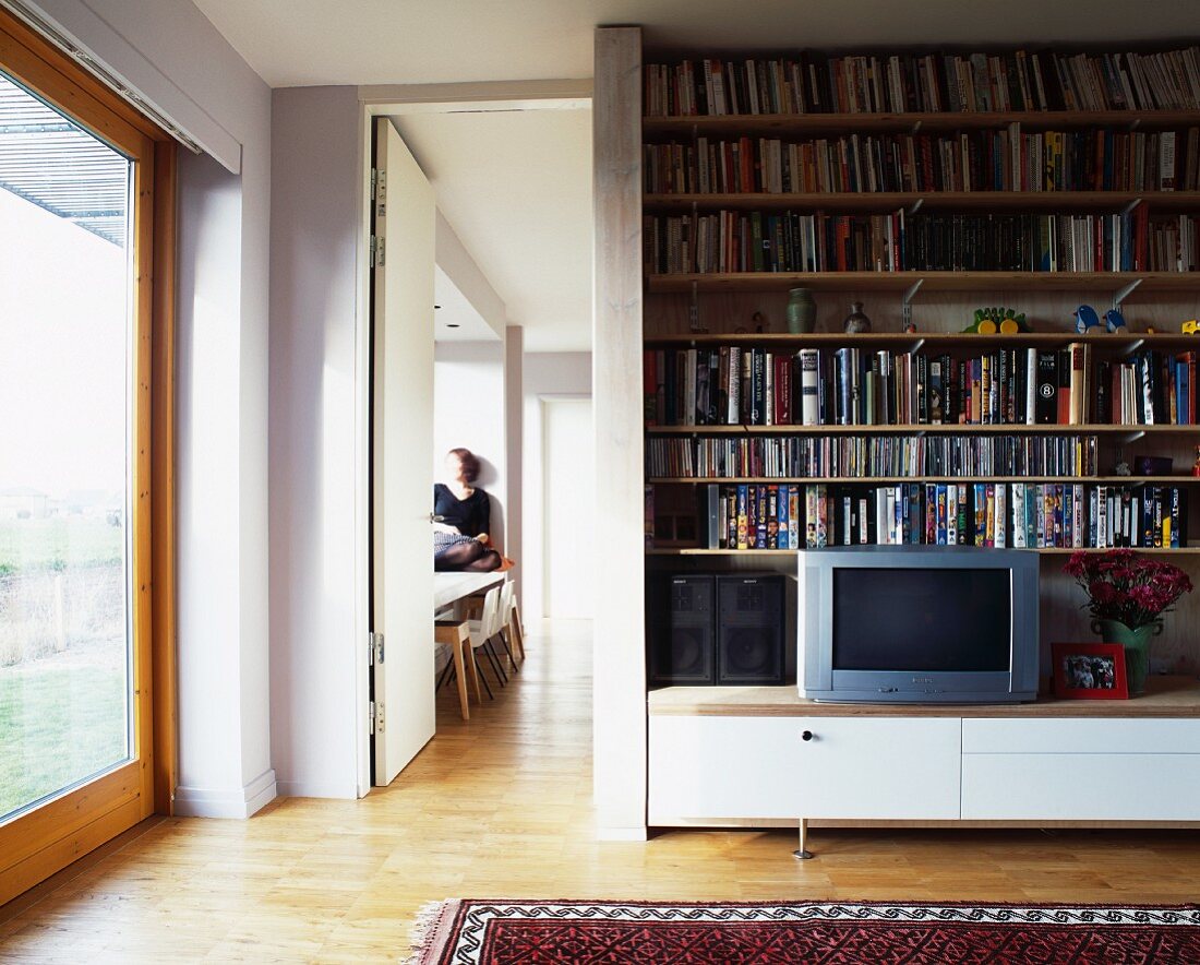 Bookcase and TV on low sideboard next to open door