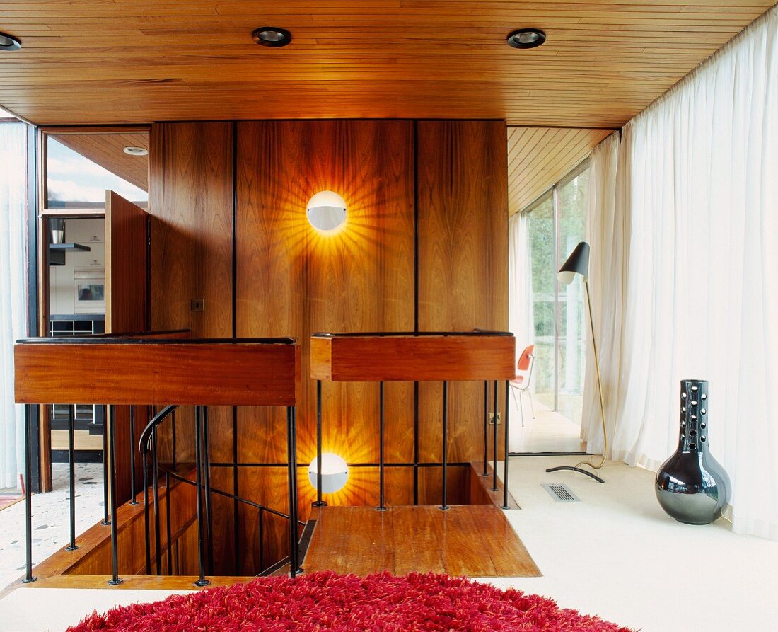 Open head of staircase in front of wood-panelled wall in living space