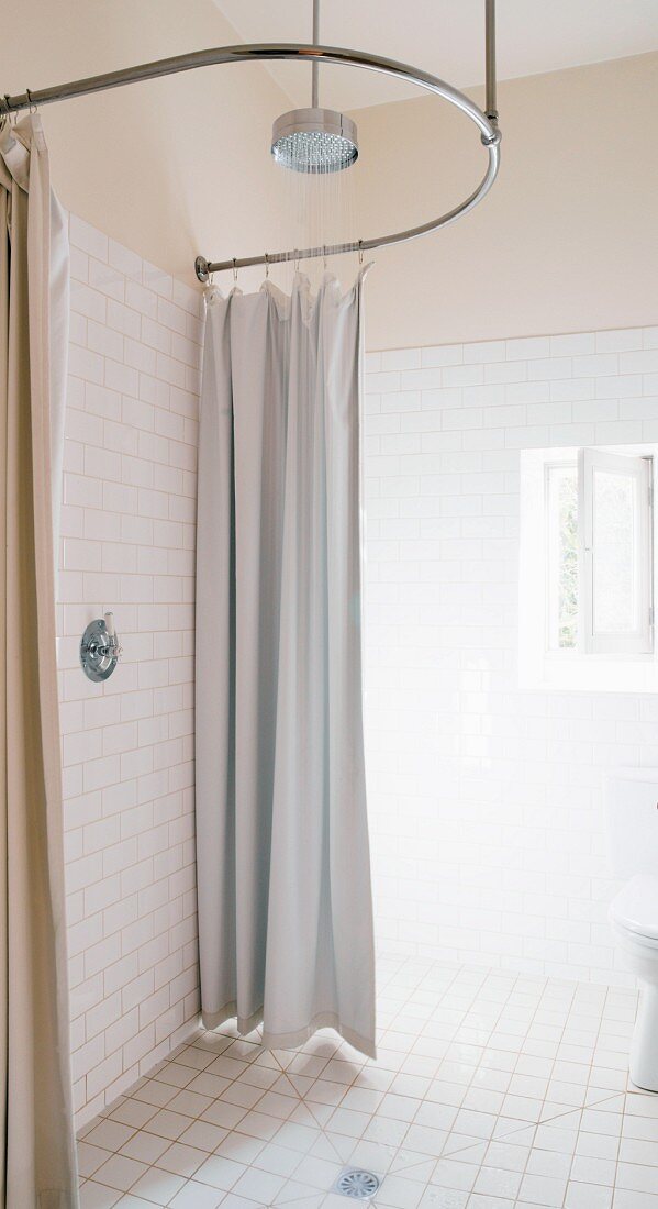 Simple, modern shower with curtain hung on suspended, curved steel tube