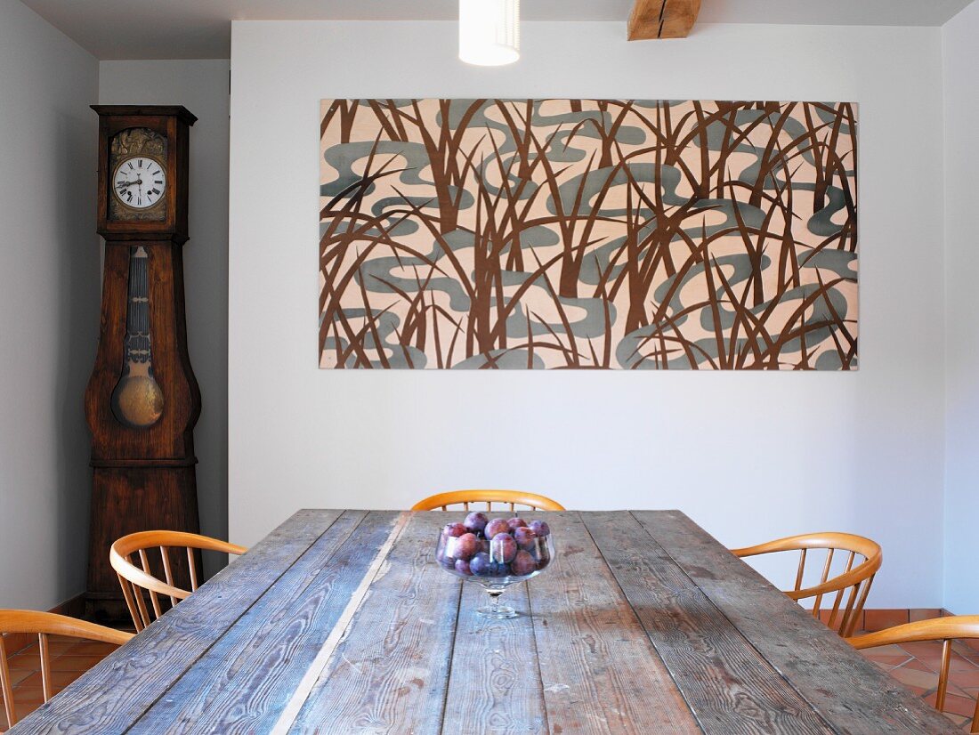 Rustic dining table and chairs in front of abstract picture on wall