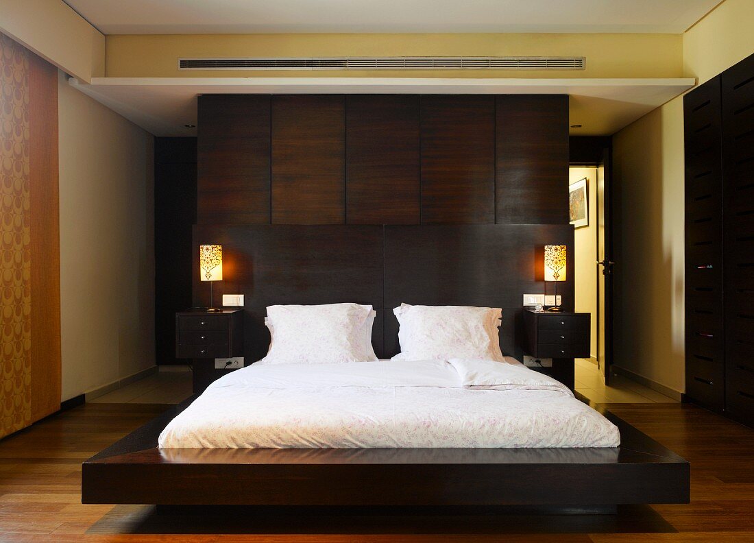 Freistehendes Doppelbett mit Rückwand aus dunklem Holz