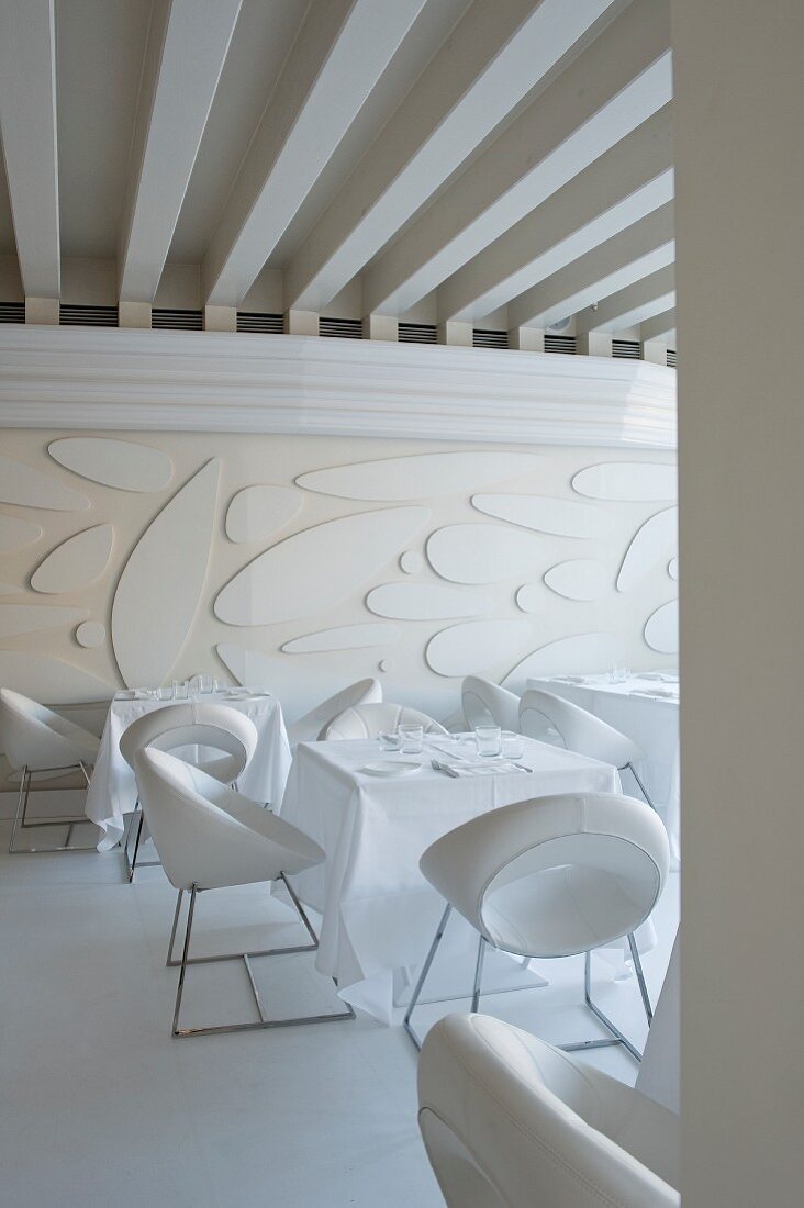 Weisser Speisesaal in venezianischem Hotel mit Designerstühlen, modernem Wandrelief und expressiver Deckengestaltung