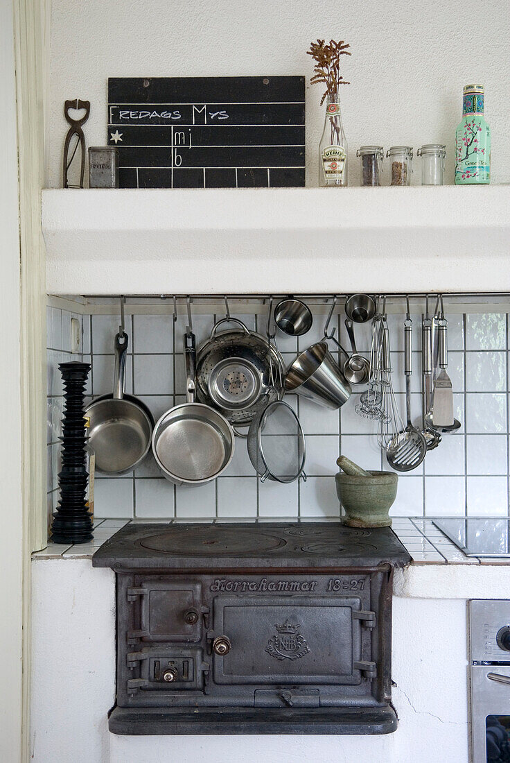 Kitchen corner with old cast iron stove and suspended cooking utensils
