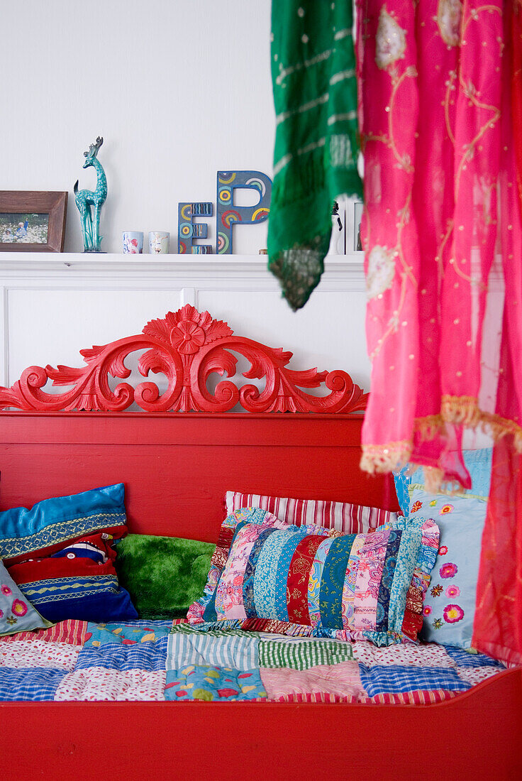Red daybed with colorful pillows and decorated headboard