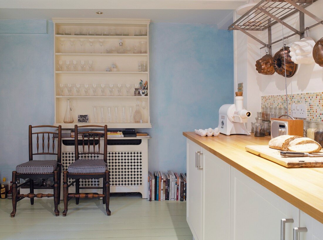 Eine Küche mit weißem Wandregal an blauer Wand