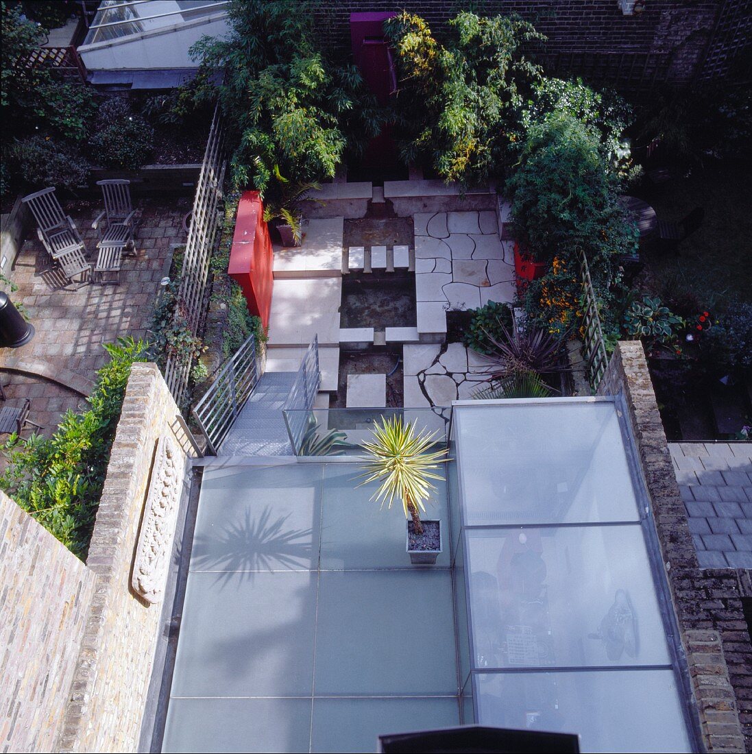 Aufsicht auf Terrasse mit Glaspanelen als Bodenbelag und zweite Terrassenebene mit Steinbelag