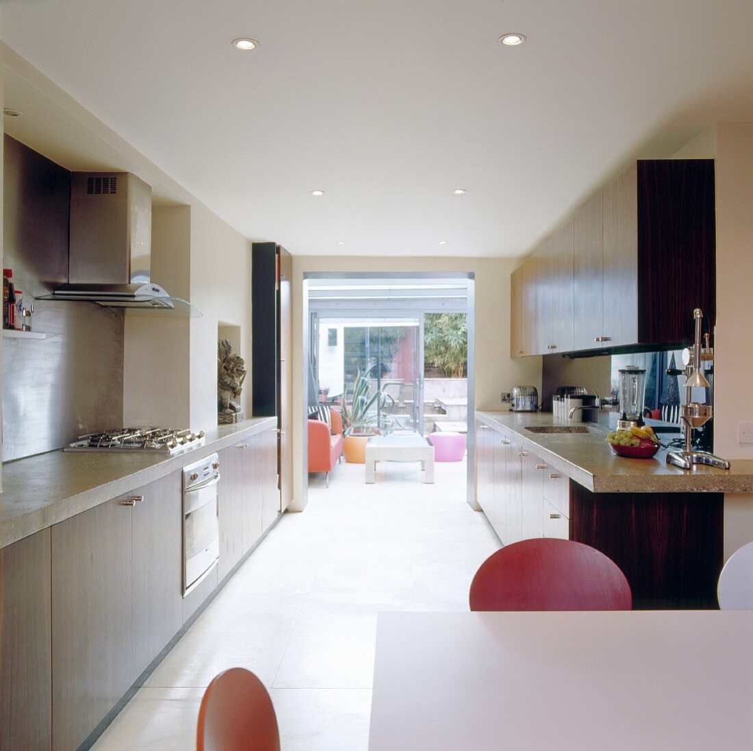 Küchenflucht mit offener Terrassentür und Blick auf farbigen Kleinmöbeln