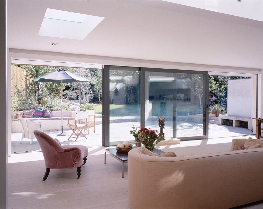 Polstermöbel Sammlerstücke in modernem Wohnraum mit breiter Glasschiebefront und Blick auf sonnige Terrasse