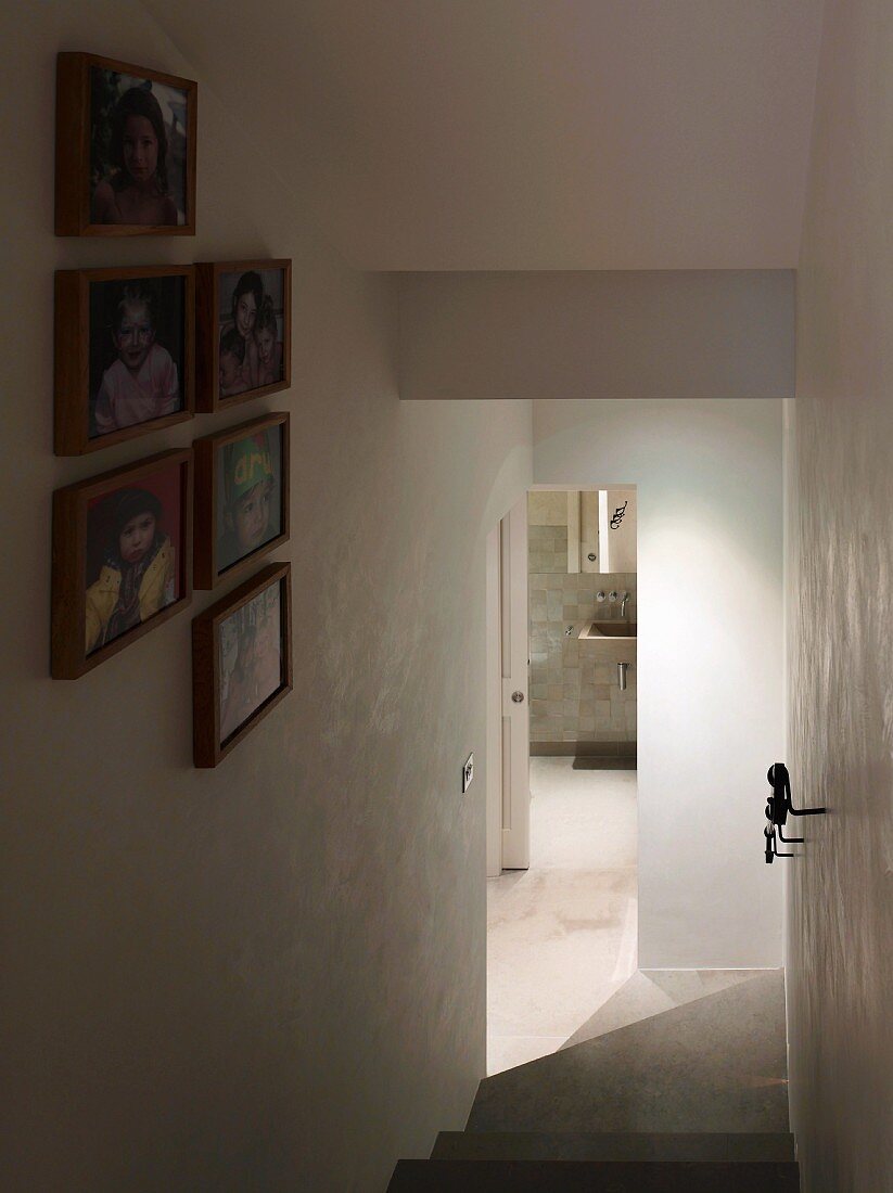 Staircase with collection of framed photographs and view through open bathroom door