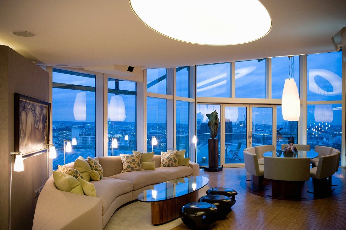 Imposanter Raum mit Wohn- und Essbereich und grosser Fensterfront in Abendbeleuchtung