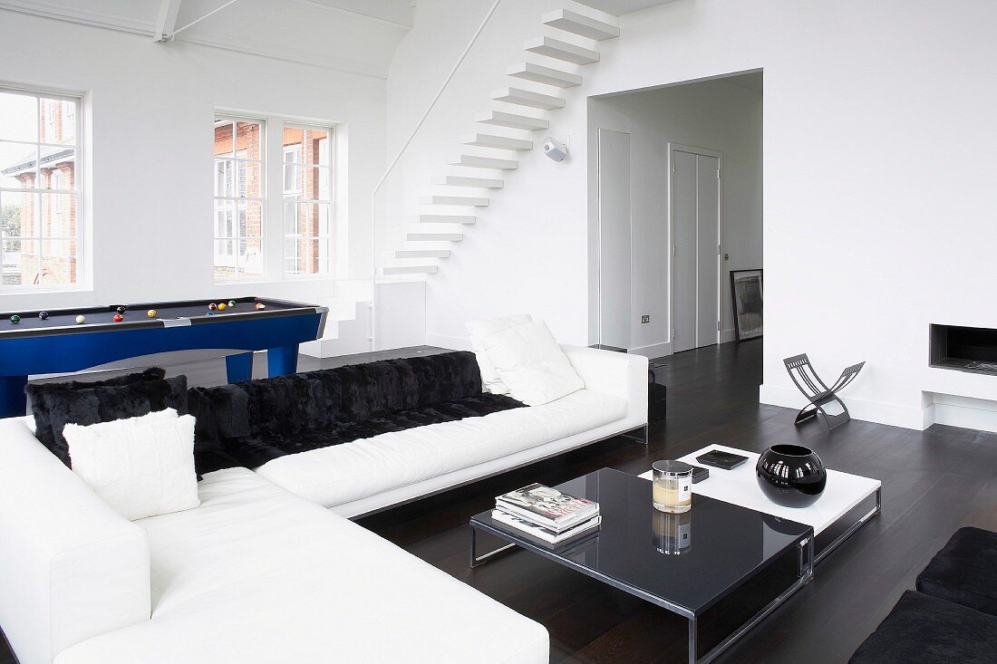 Wohnzimmer mit Sofa, Billardtisch & freischwebender Treppe