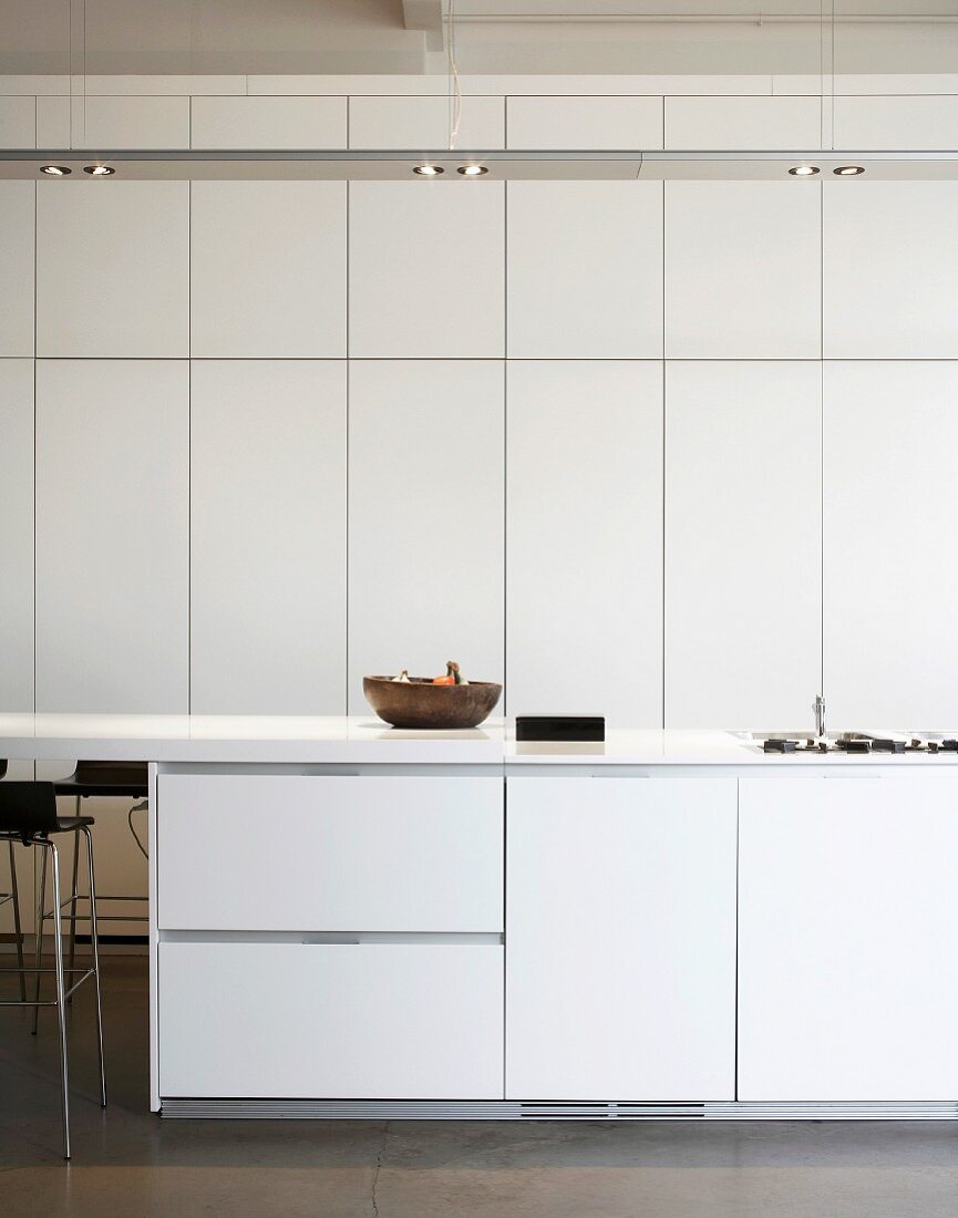 weiße Küche mit raumhohen Einbauschränken & Deckenlampe
