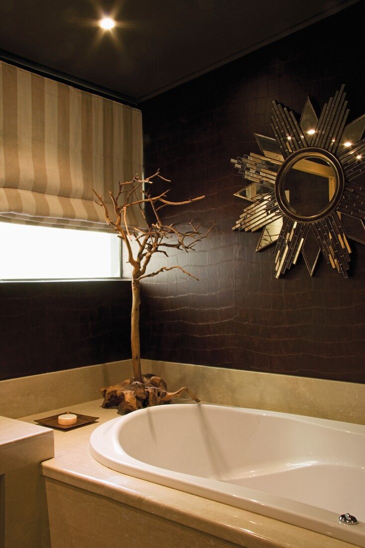 Sonnenförmiger Spiegel über der Badewanne in Badezimmer mit dunkelbraunen Wänden