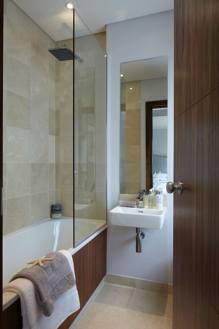 Bathtub with glass partition next to sink in bathroom