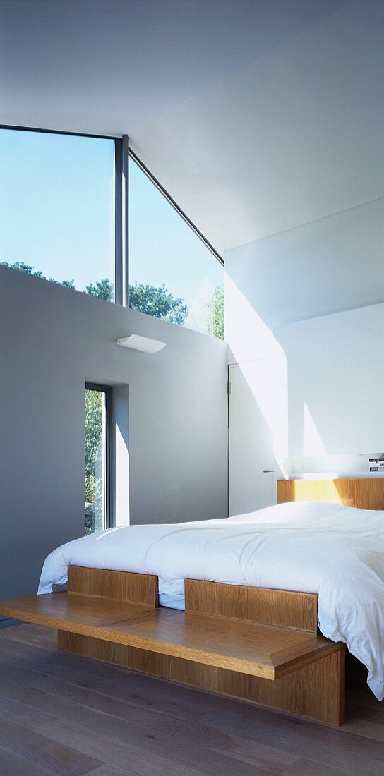 Modernes Bett aus Holz mit Oberlicht im Dachraum eines zeitgenössischen Hauses