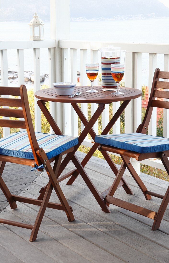 Runder Tisch mit zwei klappbaren Stühlen auf einem Balkon