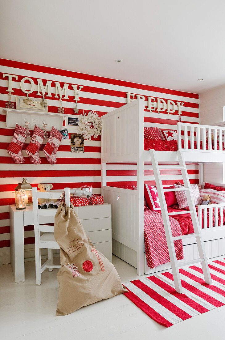 Weisses Stockbett vor rotweiss gestreifter Wand und passendem Teppich im Kinderzimmer