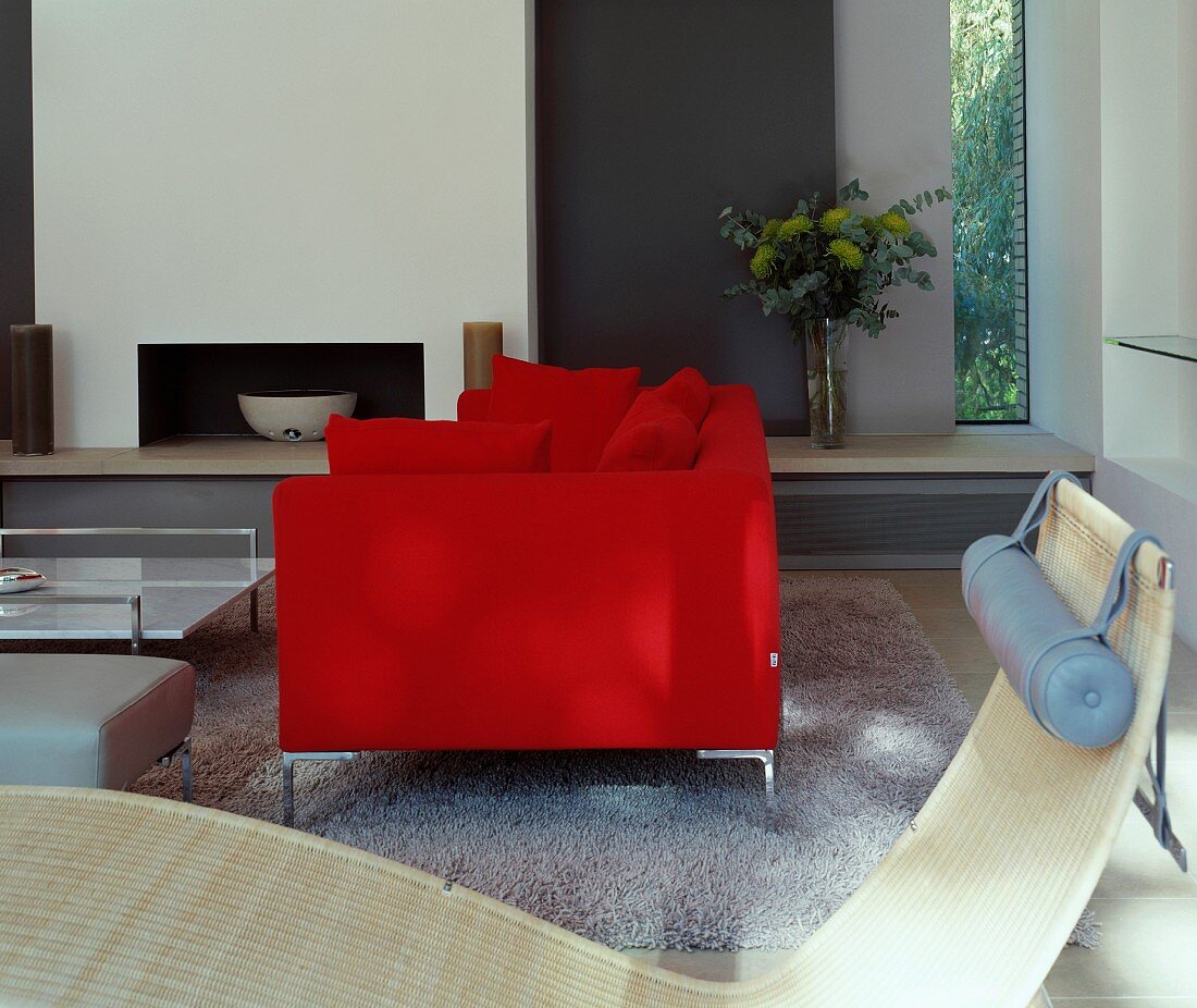 Red, modern sofa in front of fireplace in contemporary house
