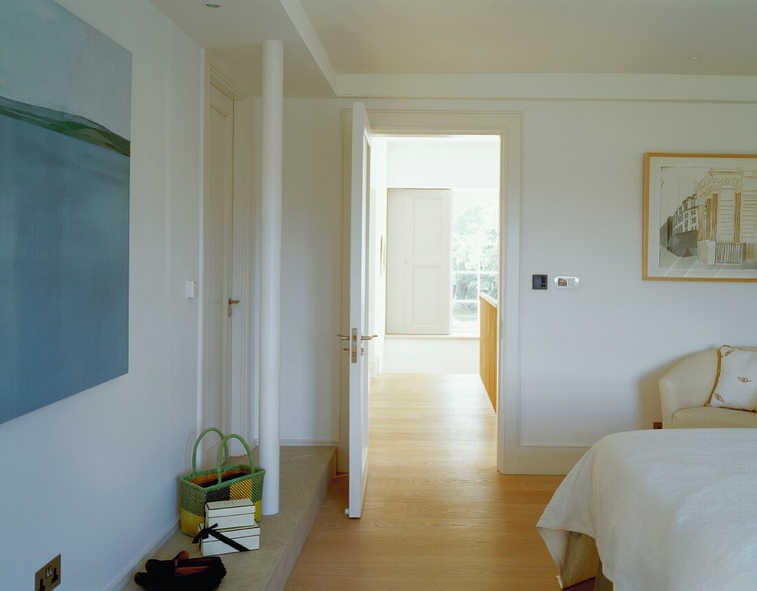 Modernes Schlafzimmer mit Blick durch offenstehende Tür ins Treppenhaus