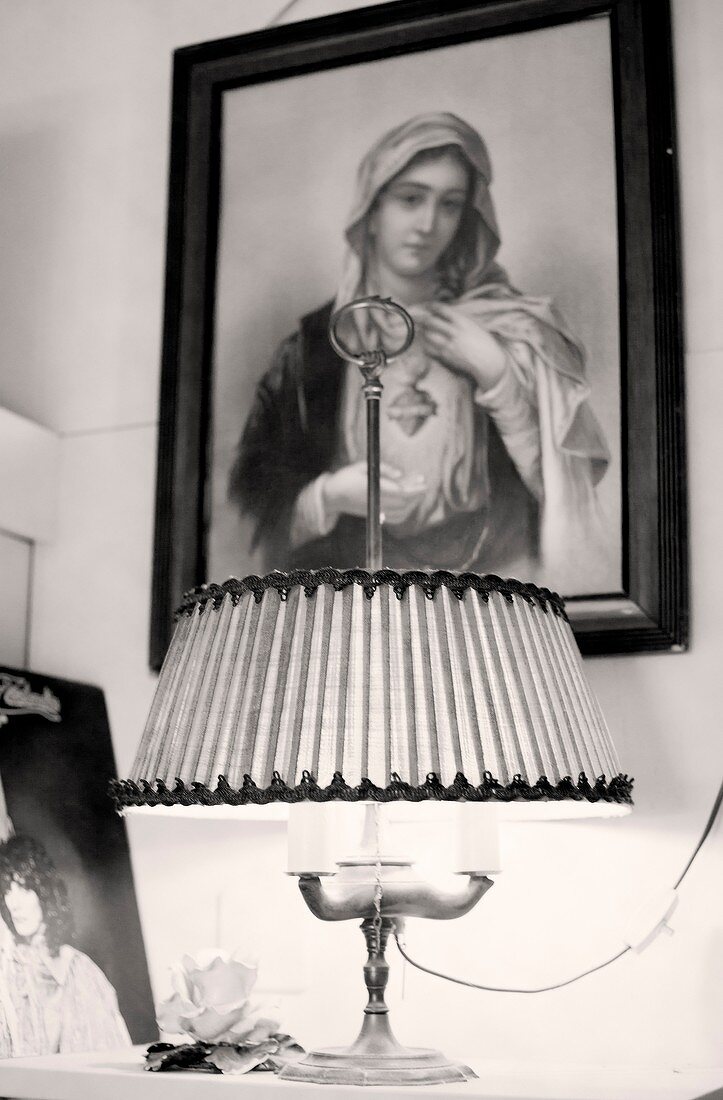Religiöses Bild über einem Nachttisch mit antiker Tischlampe hängend